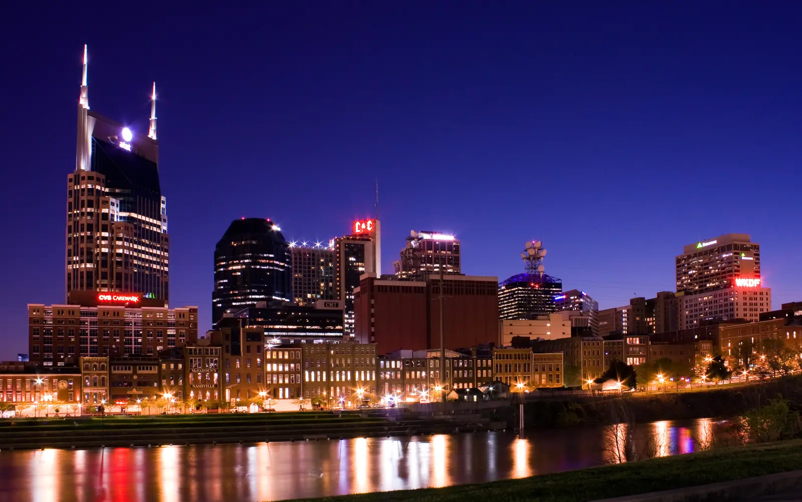 Downtown Nashville skyline illuminated at night across the Cumberland River.