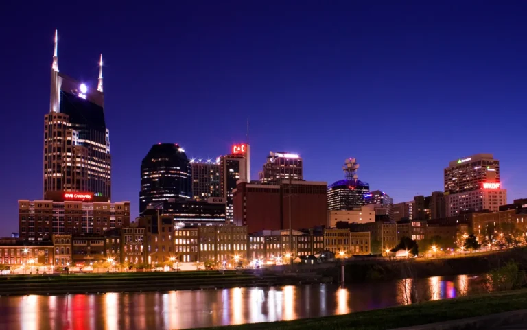 Downtown Nashville skyline illuminated at night across the Cumberland River.