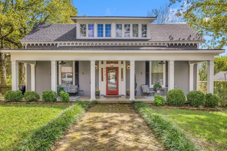Gray home with a full-width covered porch, white columns and a red front door.