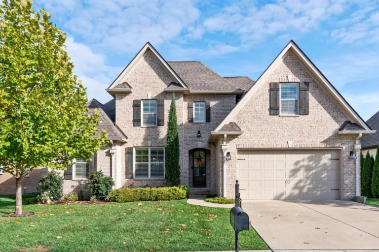 Two-story brick home with gabled rooflines, dark shutters and a two-car garage.