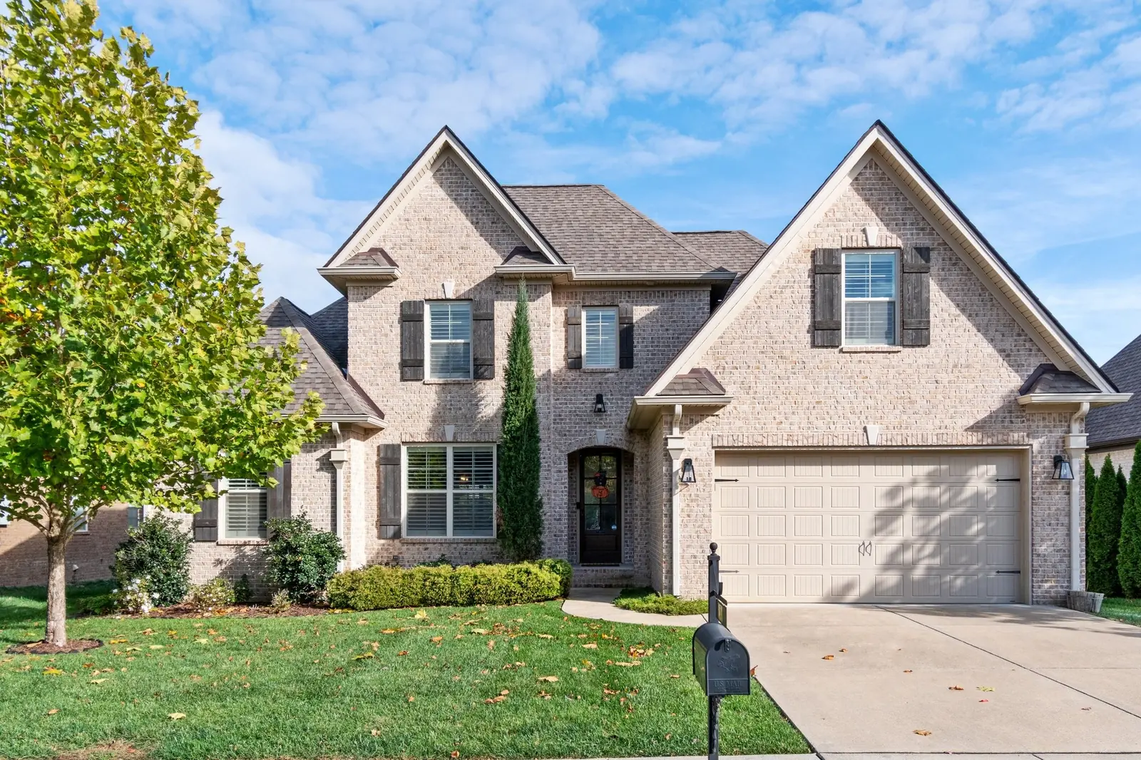 Two-story brick home with gabled rooflines, dark shutters and a two-car garage.