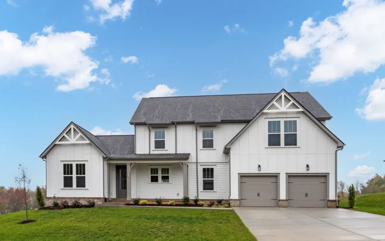 Two-story white home with board-and-batten siding and two garage doors.