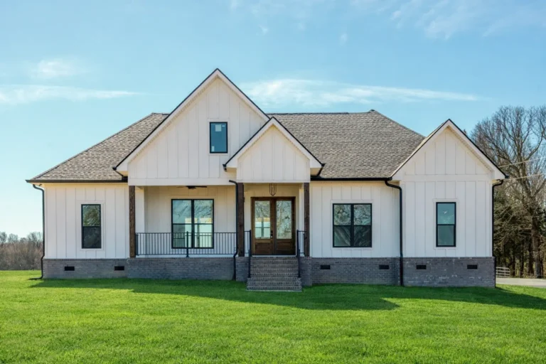 White home with a raised covered porch, black railings and double wood front doors.