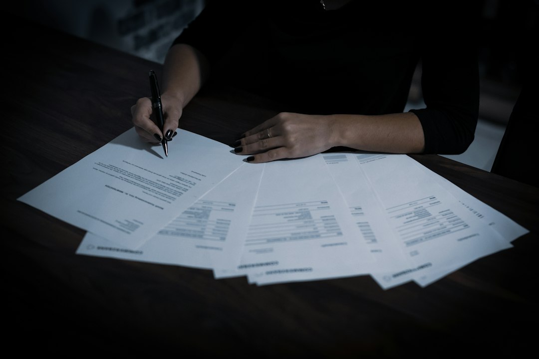 Person signing a document with a pen