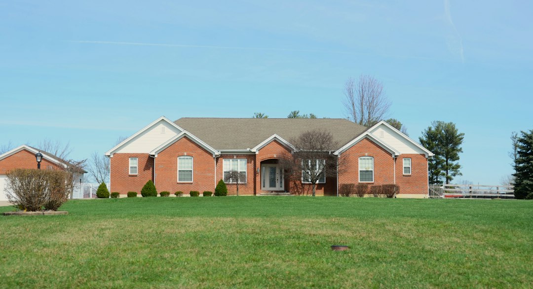 One-story red-brick home with a broad lawn; illustrative stock photograph