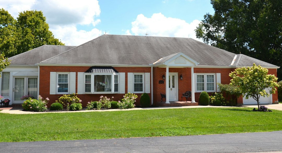 Red-brick ranch house with white trim and a front porch; illustrative stock photograph