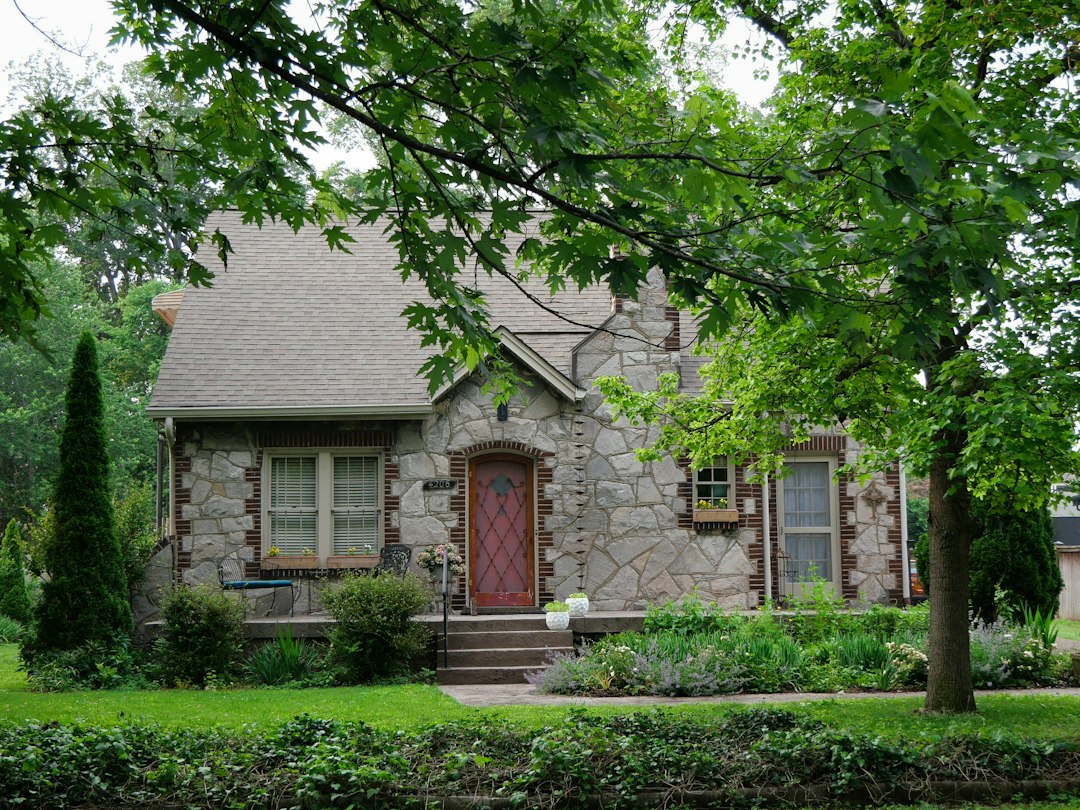 Stone cottage with a red front door framed by leafy trees in Sylvan Park, Nashville